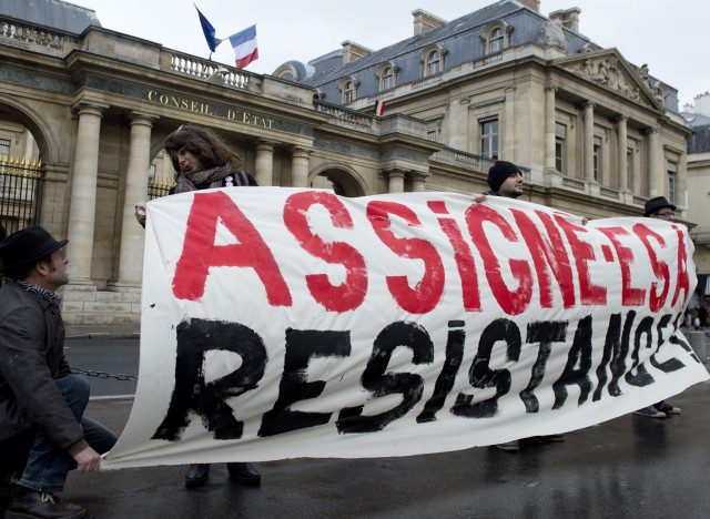 People, holding a placard reading "summoned to resist", protest outside of the French Council of State (Conseil d'Etat) in Paris on December 11, 2015 against house arrests. The highest French administrative courthouse is considering on December 11 seven cases of house arrest of environmental activists which have occured since the beginning of the state of emergency that followed the deadly November Paris attacks. / AFP / ALAIN JOCARD